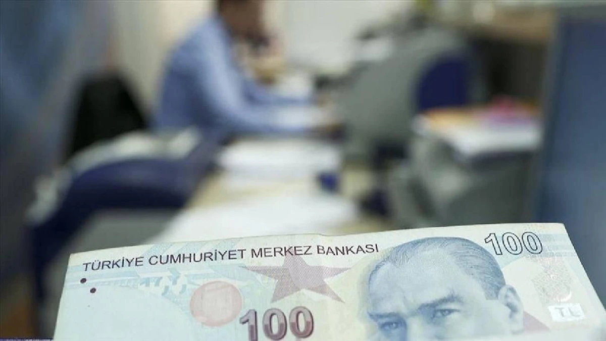 Ön planda 100 liralık banknot ve arka planda çalışma ortamı