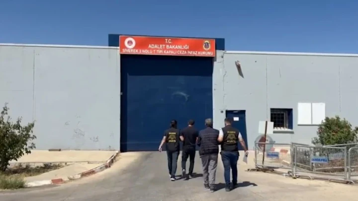 Görevliler, bir kişiyi cezaevi girişine doğru götürüyor