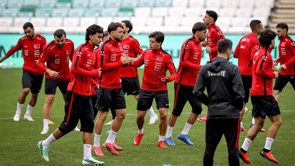 Antrenman sahasında kırmızı üstlü futbolcular taktik çalışma yapıyor