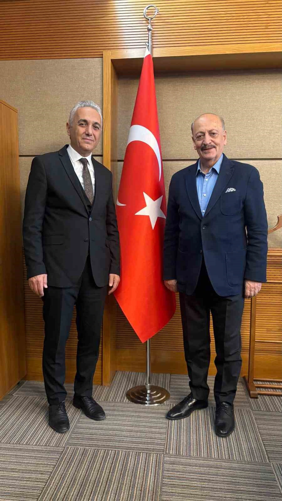 Adil Kurban ve Vedat Bilgin, Türk bayrağının önünde yan yana duruyor