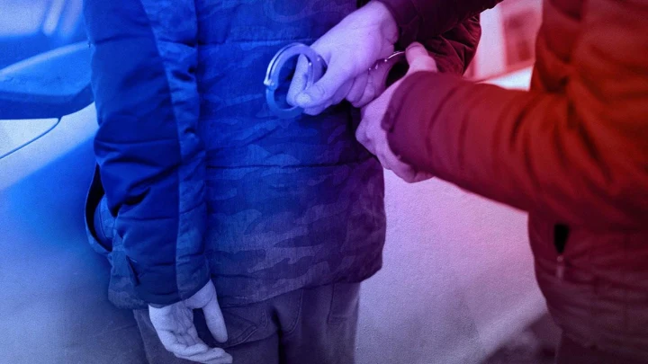 Bir kişinin ellerine kelepçe takılırken çekilmiş temsili polis operasyonu görseli