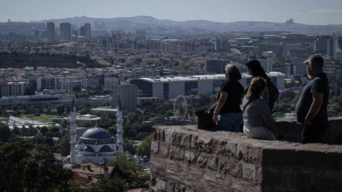 Ankara şehir manzarasına bakan taş duvar üzerinde oturan insanlar