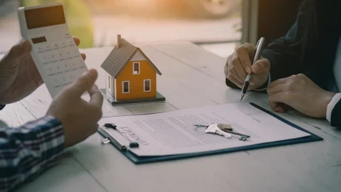 Kira sözleşmesi ve konut maketi üzerinde hesaplama yapan kişiler