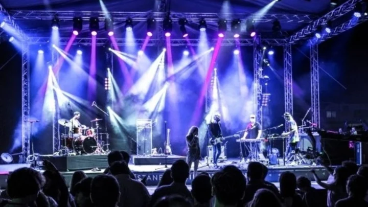Sahne ışıkları altında performans sergileyen müzik grubu ve izleyiciler