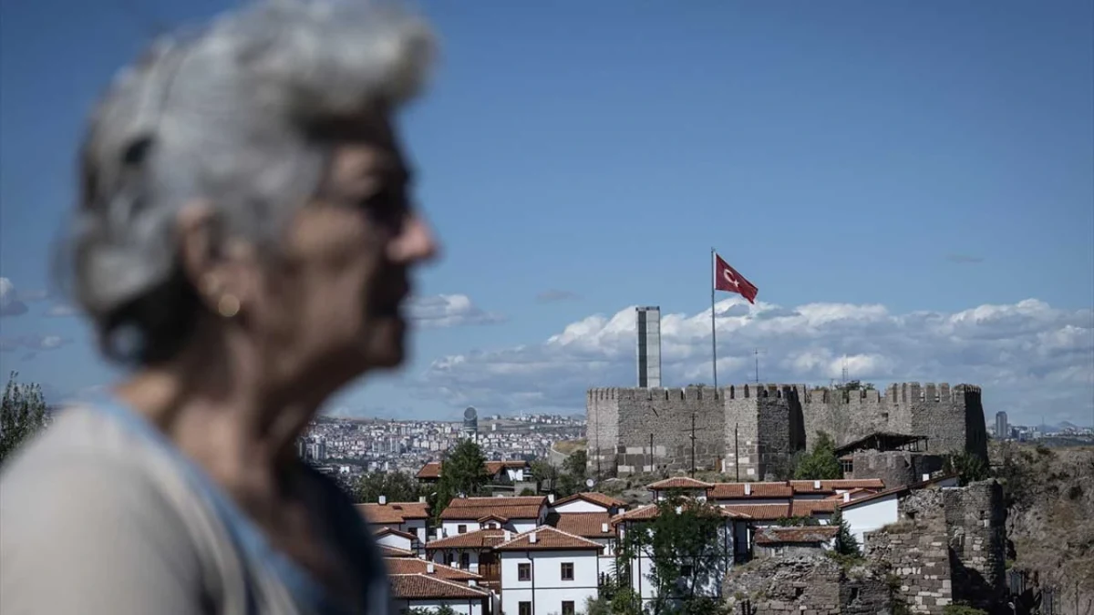 Ankara Kalesi ve çevresindeki tarihi evler, ön planda yaşlı bir kadın siluetiyle görülüyor.