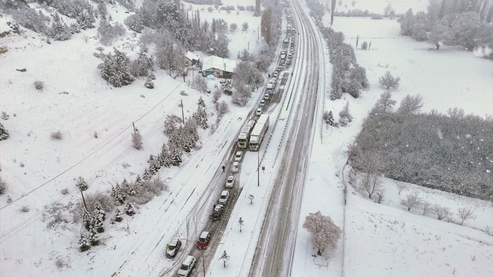 Kar yağışı altında uzanan yol ve çevresindeki beyaz örtüyle kaplı alanlar