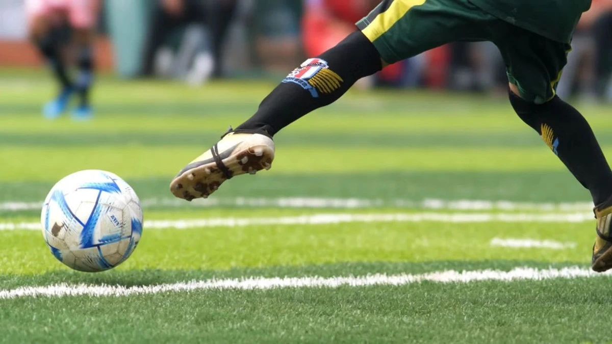 Çim sahada topa doğru koşan futbolcunun bacakları