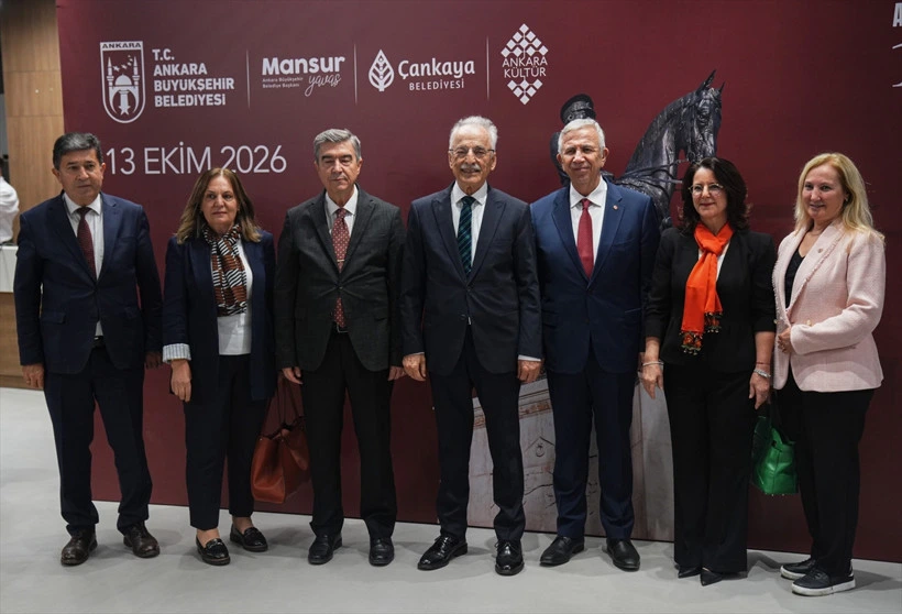 Resepsiyona katılan konuklar etkinlik panosu önünde toplu fotoğraf çektiriyor.