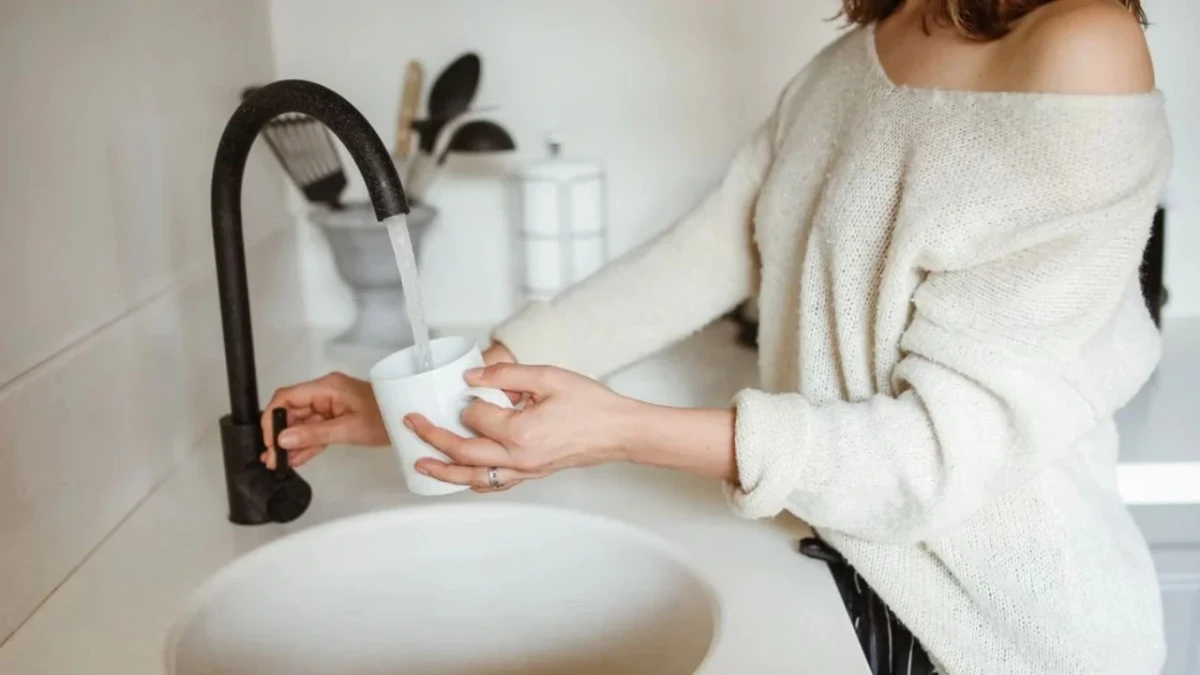 Lavabodaki musluktan su dolduran bir kişi