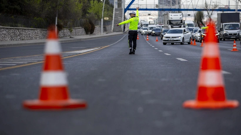 Trafik görevlisi, koniler ve araçlar arasında yolu yönlendiriyor.