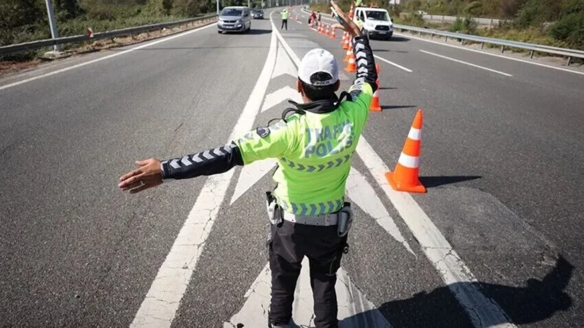 Trafik görevlisi, konilerle ayrılan yolda araçları yönlendiriyor.