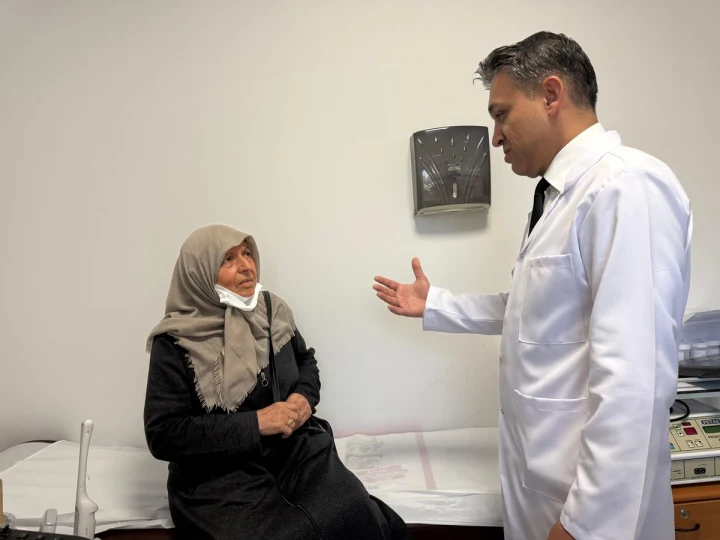 Muayene odasında oturan hasta ile konuşan doktor