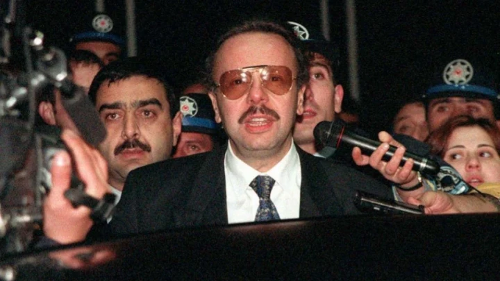 Arif Ahmet Denizolgun, basın mensuplarının ve güvenlik görevlilerinin bulunduğu bir ortamda mikrofonların önünde