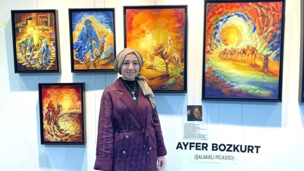 Ayfer Bozkurt, sergide kendi tablolarının önünde duruyor