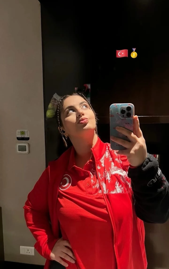 Kırmızı milli takım eşofmanı giyen Azra Sarı aynada fotoğraf çekiyor.