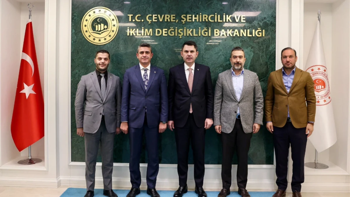 Mesut Özarslan ve Levent Koç’un da aralarında bulunduğu beş kişi, Çevre, Şehircilik ve İklim Değişikliği Bakanlığı tabelasının önünde yan yana duruyor.