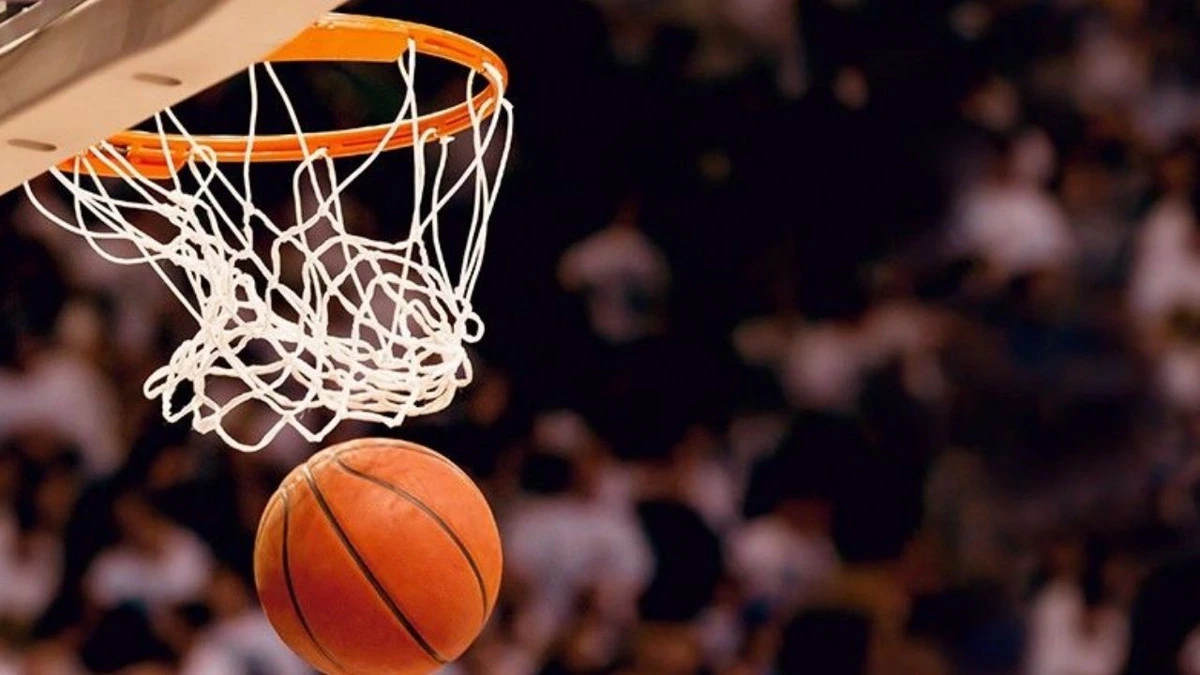 Turuncu çemberdeki fileye doğru ilerleyen basketbol topu.