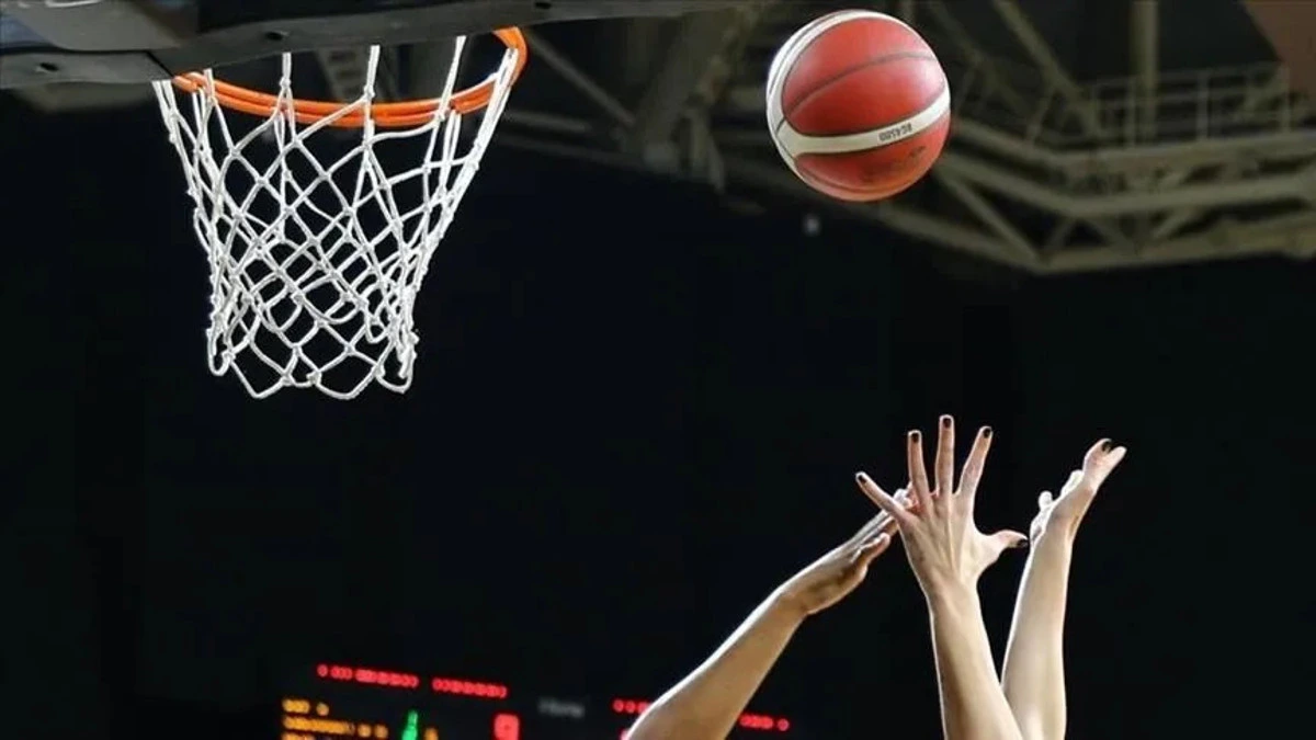 Basketbol topu potaya yönelirken oyuncular ellerini uzatıyor