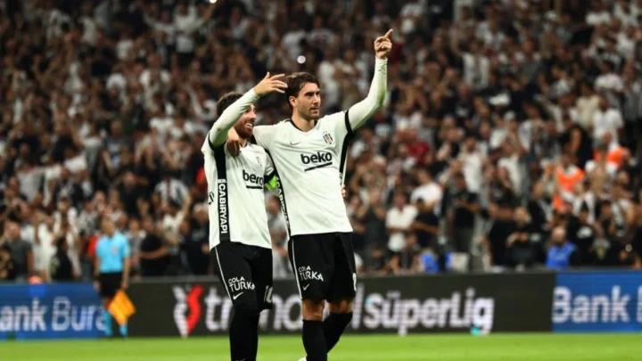 Beşiktaş forması giyen iki futbolcu, tribünlerin önünde maç sırasında sevinç yaşıyor