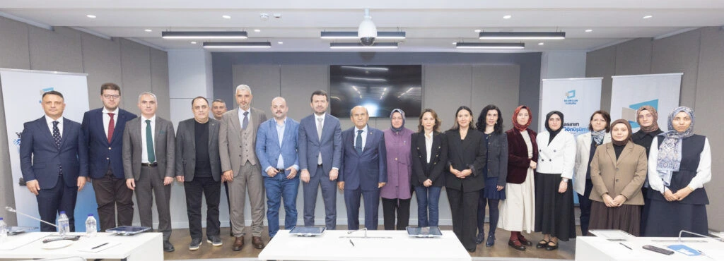 Çalıştay katılımcıları toplantı salonunda toplu fotoğraf için yan yana duruyor