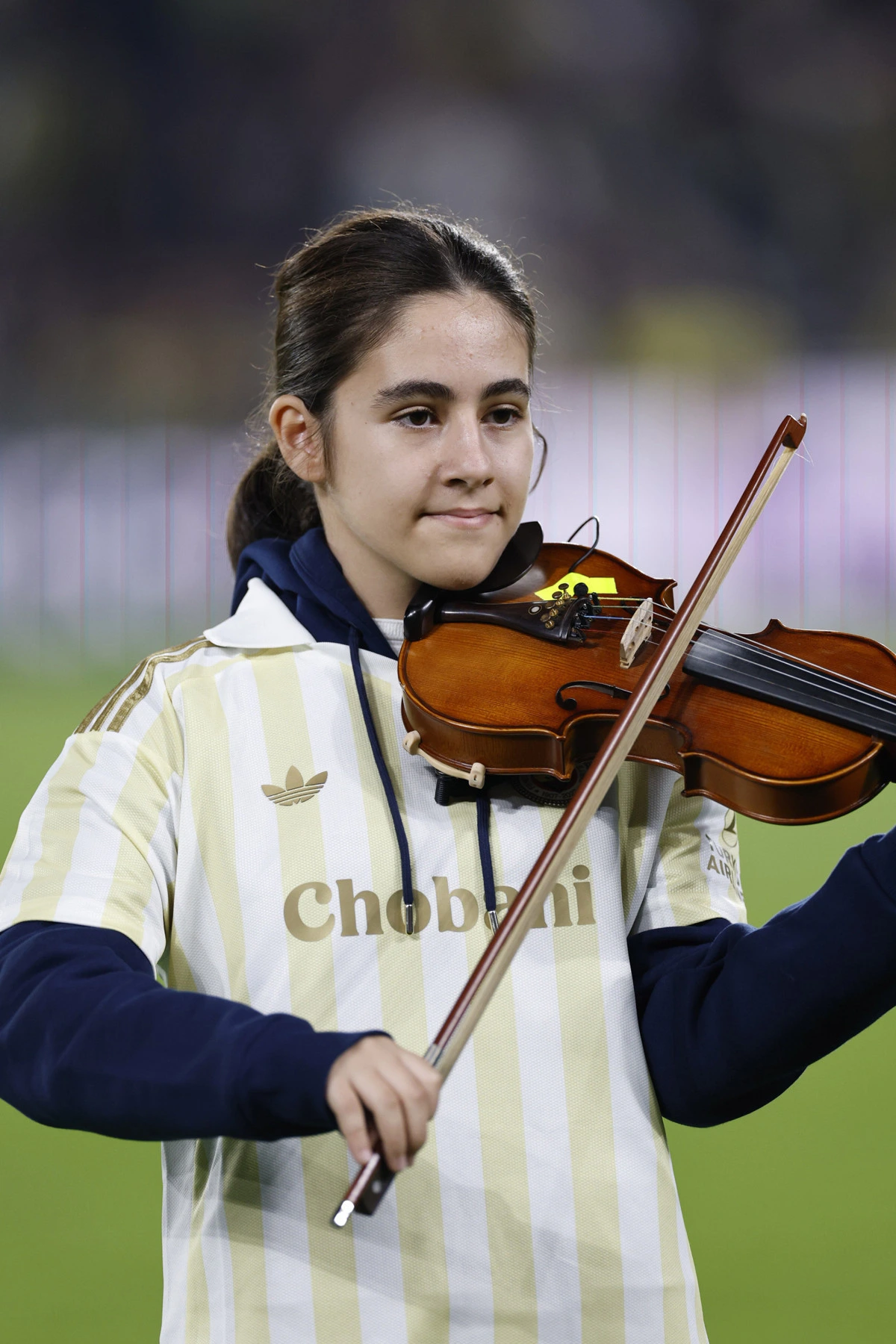 Fenerbahçe renklerini taşıyan kıyafetle keman çalan öğrenci