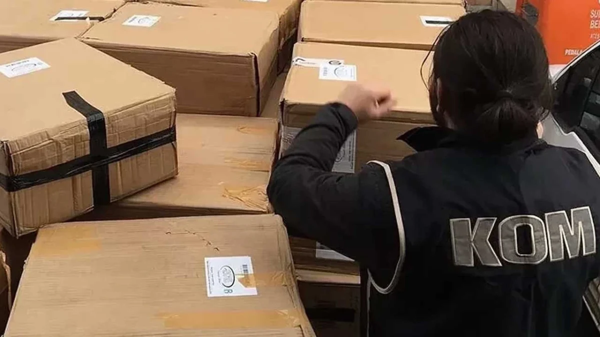 KOM yazılı yelek giyen polis, kolilerle çevrili alanda inceleme yapıyor