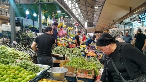 Pazar tezgâhlarında sebze ve meyve alışverişi yapan kişiler