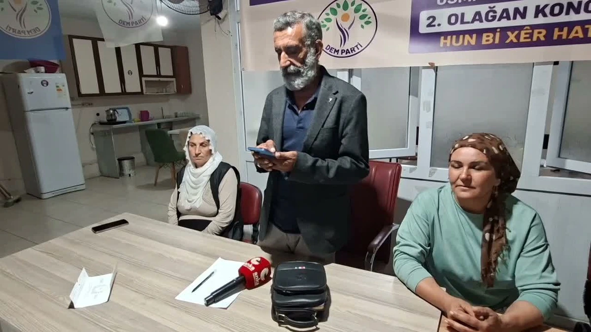 DEM Parti Osmaniye Eş Başkanı Adnan Gökçen, açıklama sırasında partililerle birlikte masada