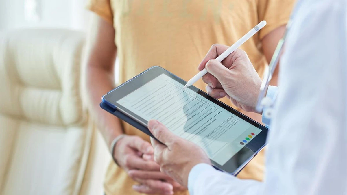 Sağlık çalışanı tablet ekranındaki formu kalemle dolduruyor