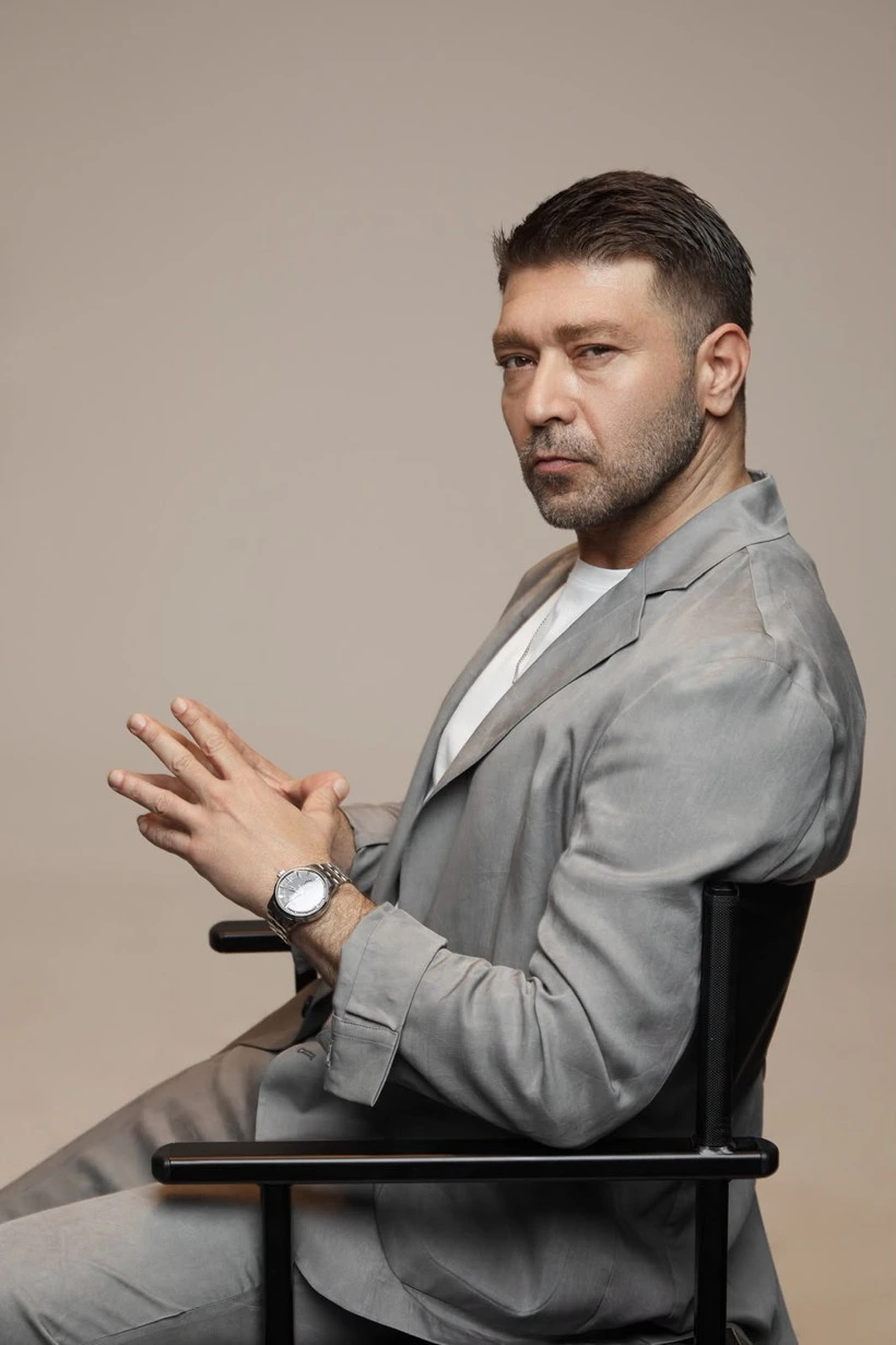 Emre Başer sandalyede otururken yana dönük poz veriyor