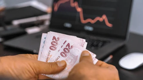 200 TL banknotları ve bilgisayar ekranında fiyat grafiği