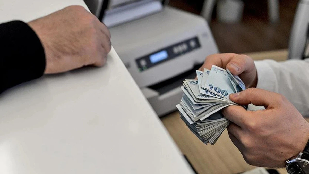 Ellerinde banknot tutan kişi ve para sayma makinesi