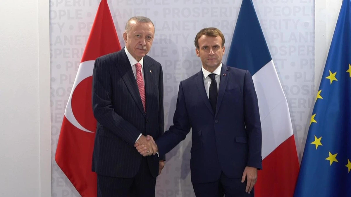 Recep Tayyip Erdoğan ve Emmanuel Macron’un bayraklar önünde el sıkıştığı fotoğraf