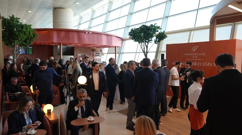 Esenboğa Havalimanı lounge alanında masalarda oturan ve ayakta sohbet eden yolcular