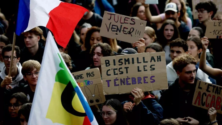 Fransa’daki kalabalık bir gösteride “Bismillah c’est les ténèbres” yazılı pankart taşıyan gençler