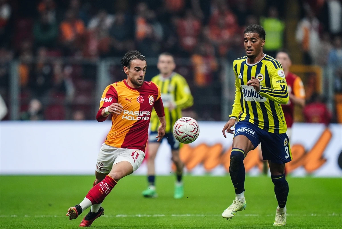 Galatasaraylı futbolcu top sürerken Fenerbahçeli oyuncu yanında koşuyor