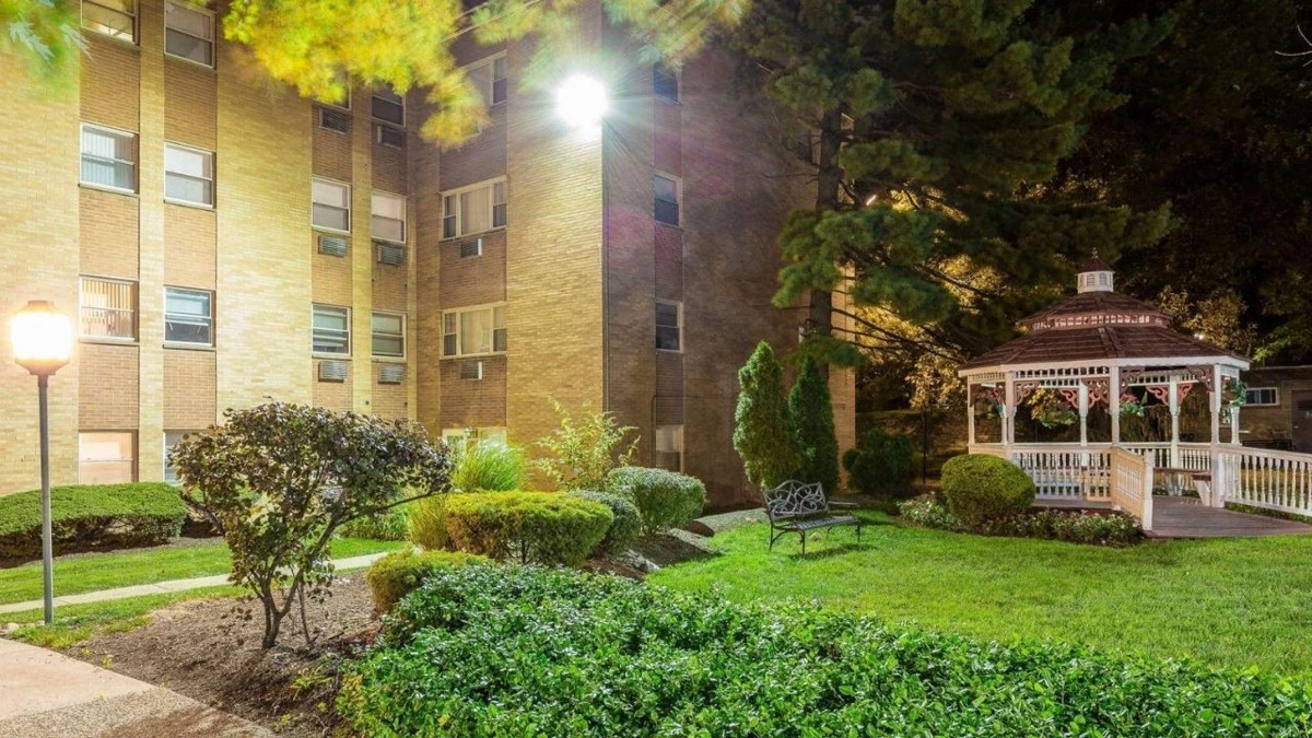 Apartmanların yanında gece aydınlatılan yeşil alan ve kamelya