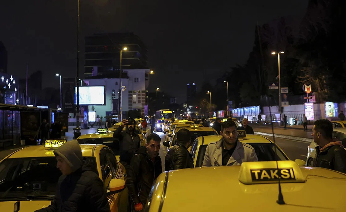 Gece bir yol kenarında bekleyen sarı taksiler ve insanlar