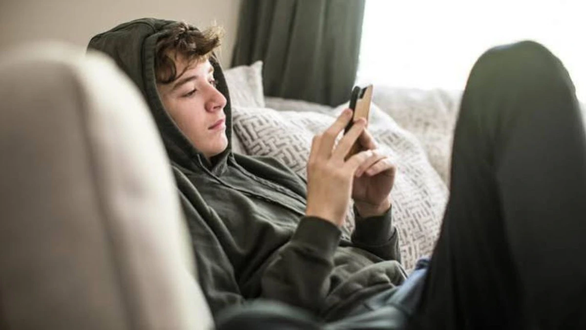 Kanepede oturup telefon kullanan genç