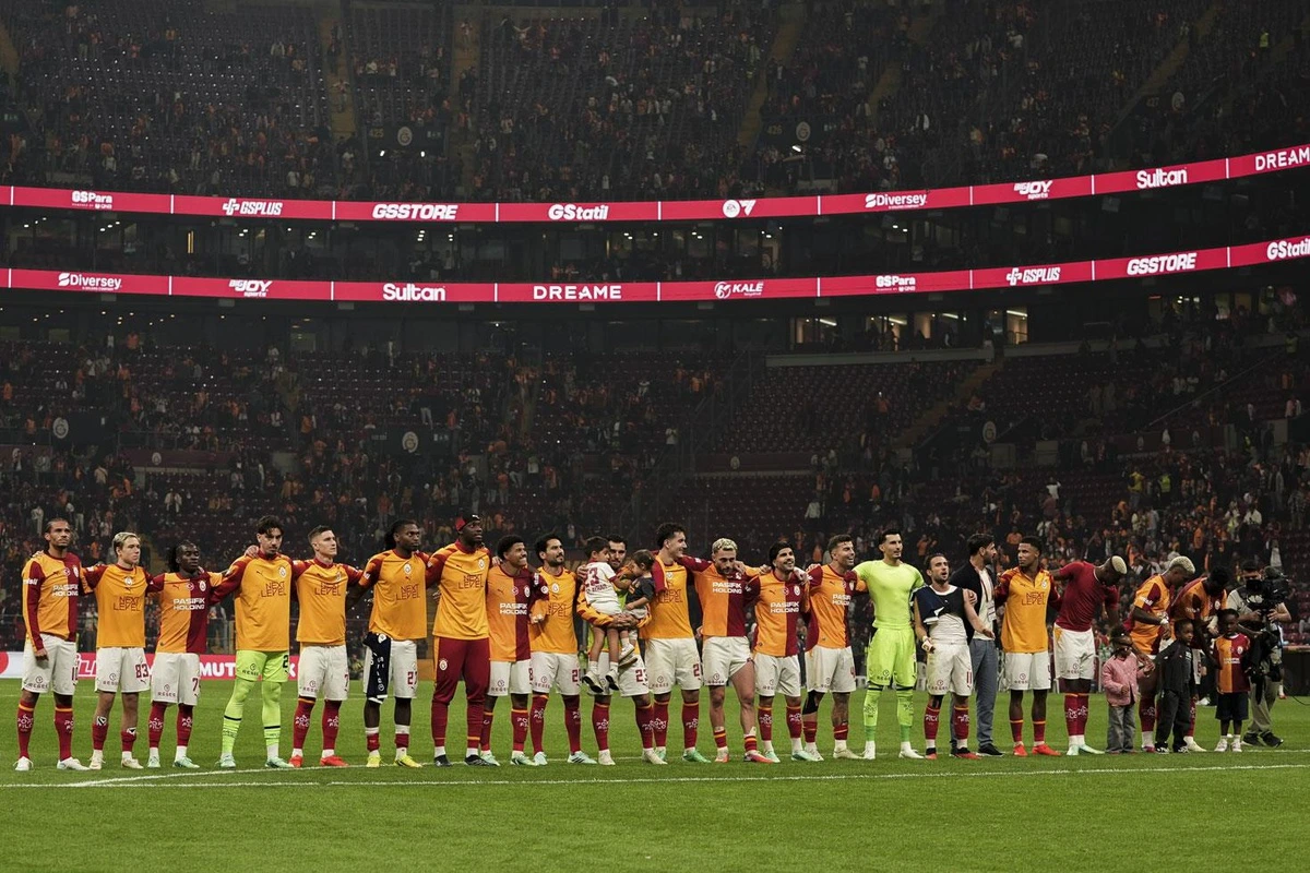 Galatasaray forması giyen futbolcular maç öncesinde sahada yan yana duruyor