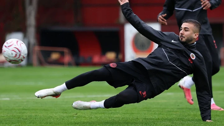 Gençlerbirliği antrenmanında siyah eşofmanlı bir futbolcu sahada topa müdahale ediyor