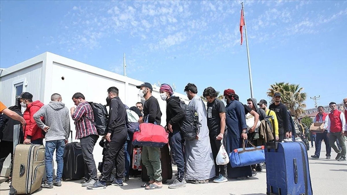 Bavullarıyla sıra halinde bekleyen insanlar
