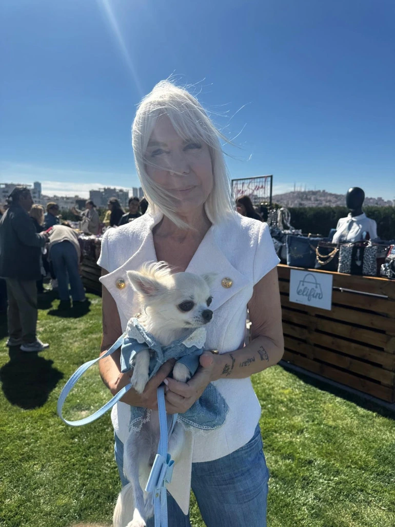 Beyaz saçlı bir kadın, mavi kıyafetli Chihuahua cinsi köpeği Suşi’yi kucağında tutuyor