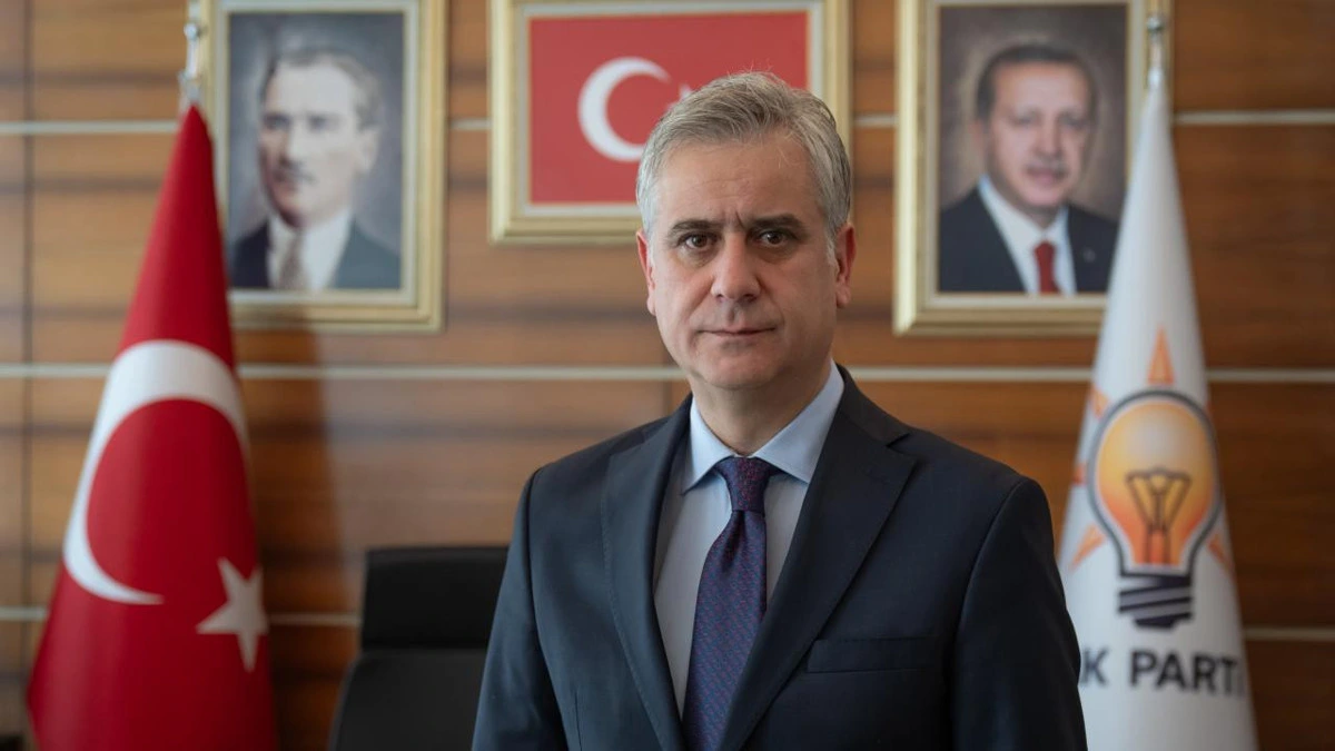 Hasan Basri Yalçın AK Parti bayrağı ve amblemi önünde