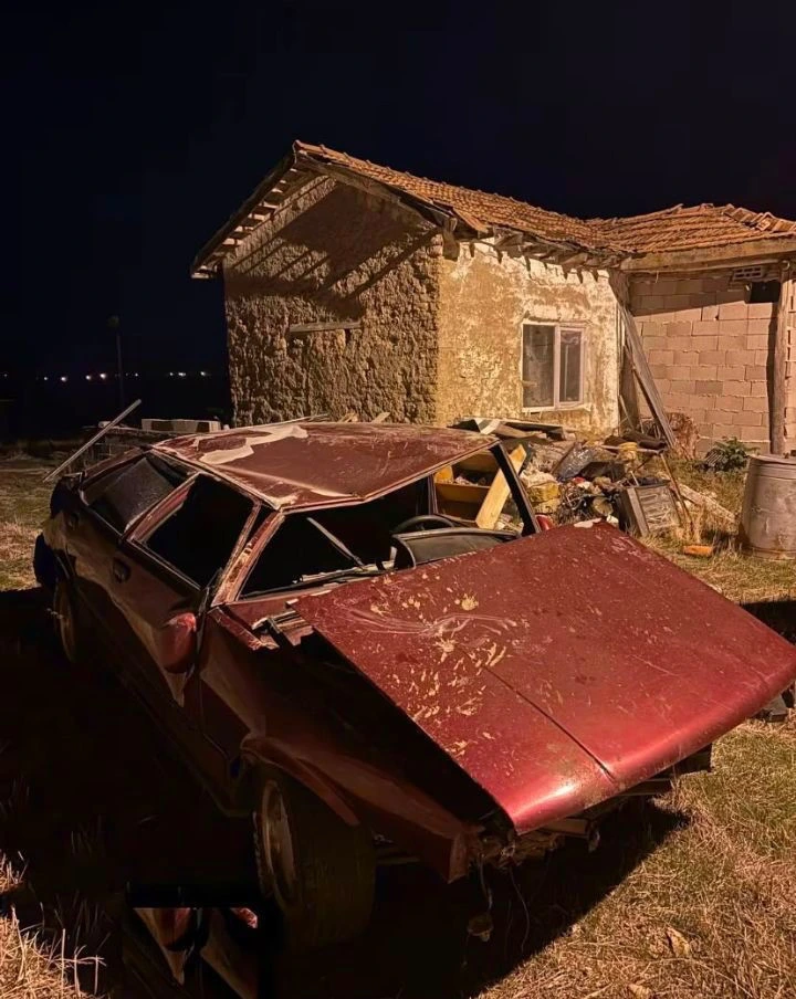 Gece bir binanın önünde ağır hasarlı kırmızı otomobil