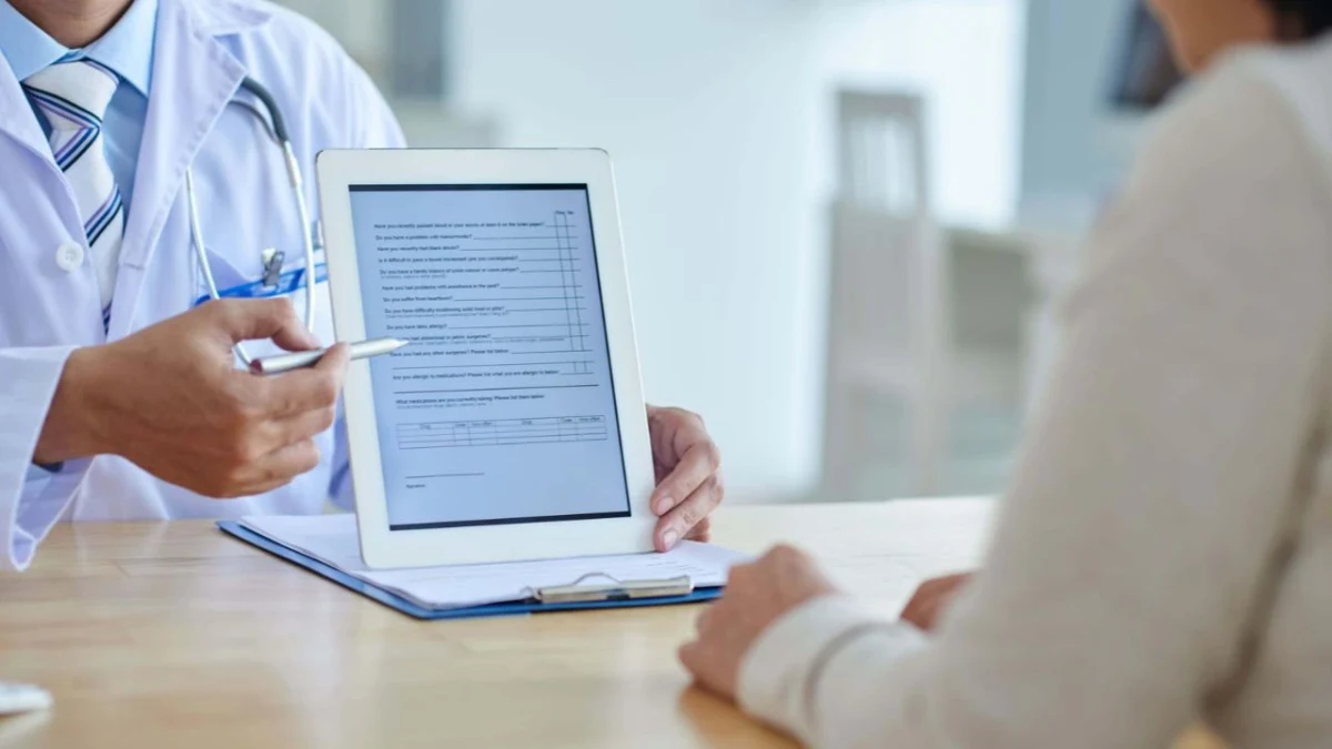 Sağlık çalışanı, hastaya tablet üzerindeki bilgilendirme formunu gösteriyor