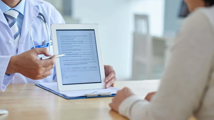 Sağlık çalışanı, hastaya tablet üzerindeki bilgilendirme formunu gösteriyor