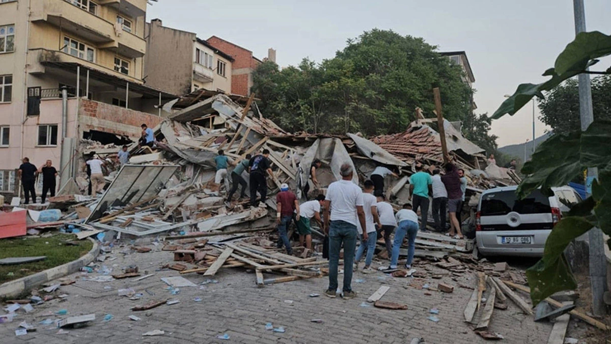 Depremde yıkılmış bir yapının enkazı çevresinde toplanan insanlar