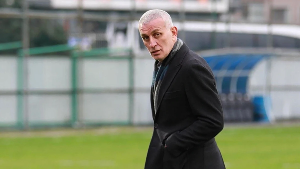 Siyah palto giymiş İbrahim Hacıosmanoğlu futbol sahası kenarında yürüyor
