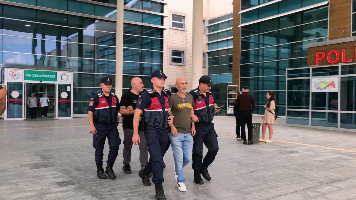 Jandarma görevlileri bir kişiyi adliye binası önünde götürüyor